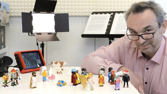 Michael Sommer sitzt am Tisch, auf dem Kamera und einige Playmobil-Figuren stehen. © Robert Haas Foto: Robert Haas