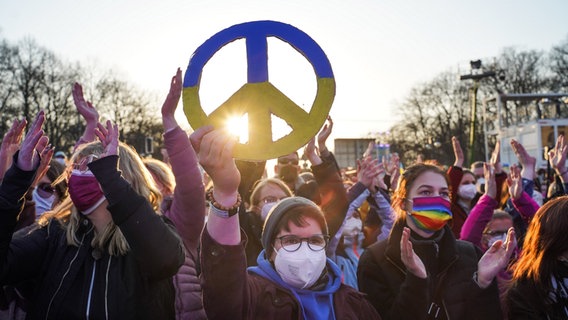 Zuschauer halten bei der Solidaritätskundgebung "Sound of Peace" ein Peace-Zeichen. © picture alliance/dpa | Jörg Carstensen 
