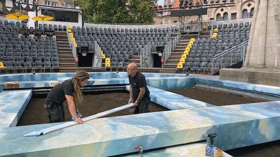 Zwei Bühnenarbeiter arbeiten an Kulissen für die "Tosca"-Produktion am Burgplatz in Braunschweig. Zwei Bühnenarbeiter arbeiten an Kulissen für die "Tosca"-Produktion am Burgplatz in Braunschweig. © NDR Foto: Bita Schafi-Neya
