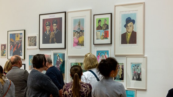 Besucherinnen und Besucher stehen vor einer Wand mit Fotografien in der Ausstellung "Ukrainian Dreamers" in Wolfsburg © Kunstmuseum Wolfsburg 