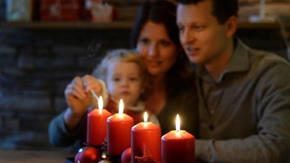 Ein junges Mädchen entzündet zusammen mit seinen Eltern Kerzen an einem Adventskranz. © BARBARA GINDL / APA / picturedesk.com Foto: Barbara Gindl