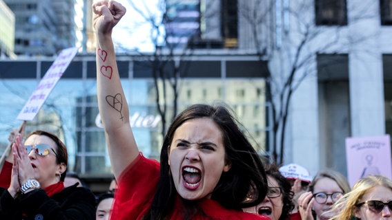 Eine in rot gekleidete Frau reckt den Arm bei einer Demonstration zum Weltfrauentag die Faust in die Luft © picture alliance / NurPhoto Foto: Anik Rahman