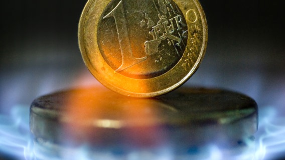Eine Euro-Münze steht zwischen Gasflammen auf einem Herd. © picture-alliance/ ZB Foto: Hans Wiedl