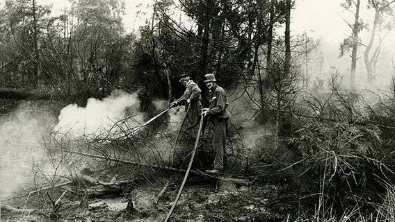 Zwei Feuerwehrleute versuchen das Feuer einzudämmen beim Brand in der Lüneburger Heide 1975.  Foto: Hildegard Markmann