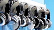 Reihe von an Haken aufgehängten Kopfhörern. © picture-alliance/dpa-Report 