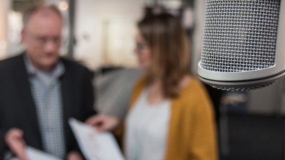 Ein Mikrofon vor zwei Menschen. © NDR Foto: Janis Röhlig
