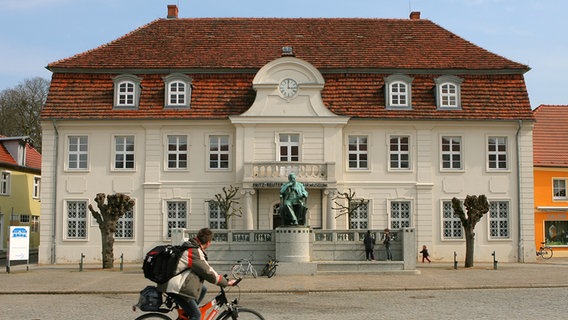 Das Fritz-Reuter-Literaturmuseum mit dem Denkmal in doppelter Lebensgröße davor (1911, Wilhelm Wandschneider) in Stavenhagen (Kreis Demmin). © dpa/ZB Foto: Bernd Wüstneck