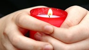 Hände halten ein brennendes Grablicht. © picture-alliance / ZB Foto: Patrick Pleul