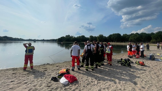 Einsatzkräfte der Feuerwehr und der DLRG stehen am Ufer des Eichbaumsees in Hamburg. © Blaulicht-News.de Foto: Blaulicht-News.de