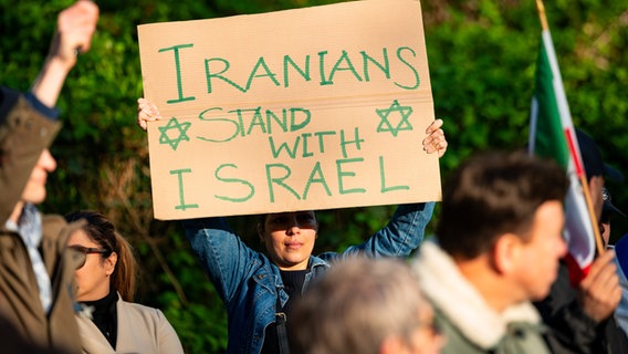 Eine Frau hält ein Plakat mit der Aufschrift "Iranians stand with Israel" während einer Kundgebung auf der Wiese gegenüber des iranischen Konsulats © dpa-Bildfunk Foto: Jonas Walzberg