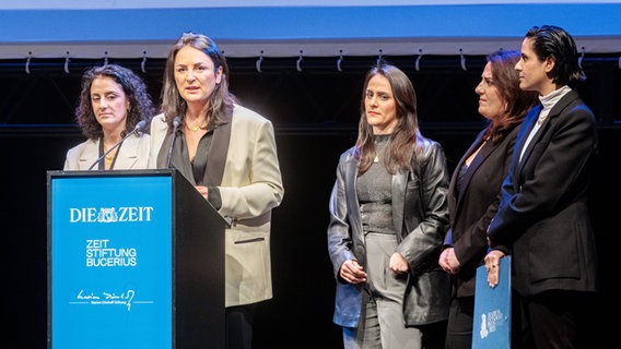 Düzen Tekkal, Gründerin der Menschenrechtsorganisation HÁWAR.help e.V., hält zwischen ihren vier Schwestern die Dankesrede für den Marion-Dönhoff-Förderpreis. Düzen Tekkal, Gründerin der Menschenrechtsorganisation HÁWAR.help e.V., hält zwischen ihren vier Schwestern die Dankesrede für den Marion-Dönhoff-Förderpreis. © Markus Scholz/dpa