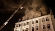Feuerwehrleute löschen von einer Drehleiter aus ein brennendes Haus in Hamburg. © dpa - Bildfunk Foto: Axel Heimken
