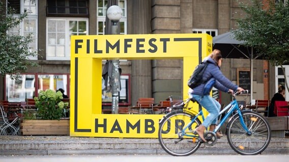Ein gelbes Logo vom Filmfest Hamburg vor dem Hamburger Abaton Kino ©  Daniel Reinhardt/dpa +++ dpa-Bildfunk Foto:  Daniel Reinhardt