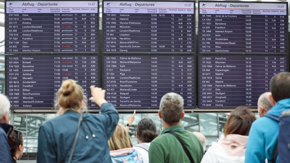 Flugreisende stehen unter den Anzeigetafeln in Terminal 1 am Airport Hamburg. © picture alliance/dpa Foto: Christian Charisius