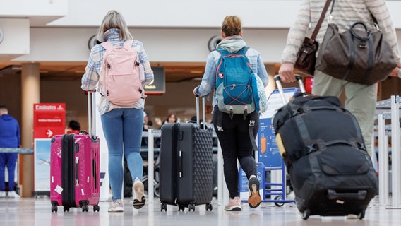 Flugreisende gehen im Flughafen Hamburg zu einem Check-In Schalter. © Markus Scholz/dpa 