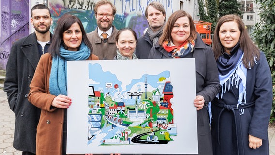 Abgeordnete der Hamburger Grünen halten zum Thema "1000 Tage grüne Fraktionsarbeit in Hamburg" das Bild eines Wandgemäldes, das die Schwerpunkte ihrer Arbeit illustrieren soll. © picture alliance / dpa Foto: Markus Scholz