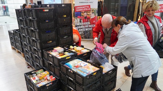 Menschen packen Lebensmittel in große Kisten, die von der Hamburger Tafel eingesammelt werden. © picture alliance 