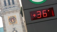 Eine Temperaturanzeige zeigt 36 Grad Celsius an. Im Hintergrund ist das Hamburger Rathaus zu sehen. © picture alliance / dpa | Bodo Marks Foto: Bodo Marks