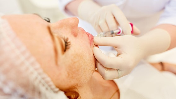 Eine Frau bekommt eine Spritze mit Hyaluronsäure in die Lippen. © Zoonar Foto: Robert Kneschke