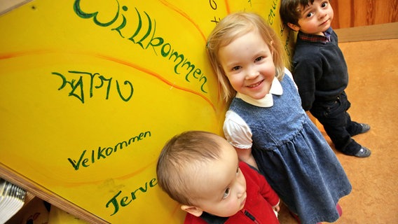 Kita-Kinder vor einer Wand auf der das Wort "Willkommen" in mehreren Sprachen steht. © picture alliance / dpa Foto: Bodo Marks