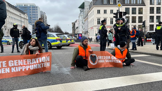 Mehrere Aktivistinnen und Aktivisten haben sich auf die Straße geklebt. © NDR Foto: Finn Kessler