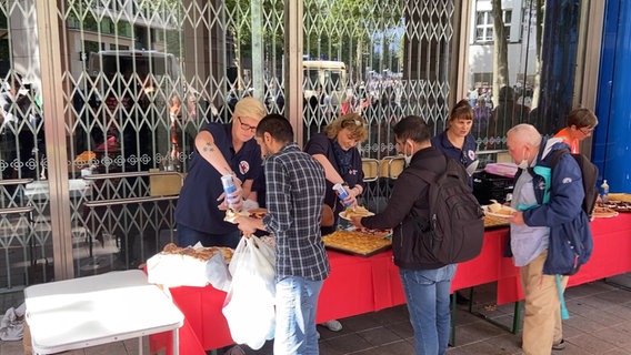 Menschen stehen am Kuchenbuffet für Wohnungslose an. © NDR 