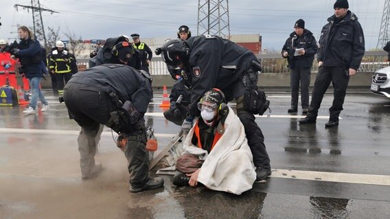 Polizisten fräsen einen Klimaaktivisten frei, der sich auf einer Brücke festgeklebt hat. © dpa-Bildfunk Foto: Steven Hutchings