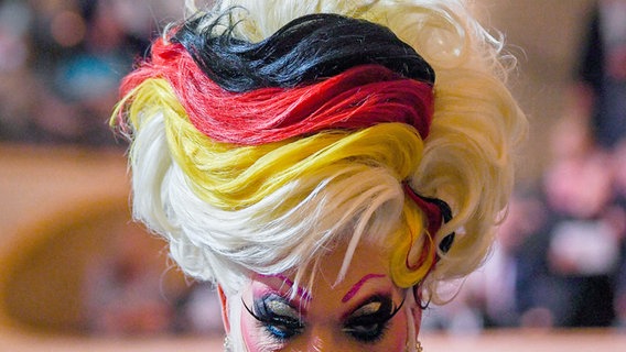 Drag Queen Olivia Jones geht mit schwar-rot-gold gefärbten Haaren zu einem Festakt anlässlich der Feierlichkeiten zur deutschen Wiedervereinigung in der Hamburger Elbphilharmonie. © picture alliance/dpa/Pool AP Foto: Gregor Fischer