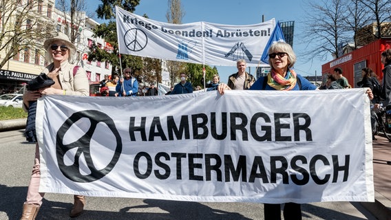 Teilnehmer des Hamburger Ostermarschs laufen mit zwei Transparenten mit den Aufschrift "Kriege beenden! Abrüsten" und "Hamburger Ostermarsch". © picture alliance / dpa Foto: Markus Scholz