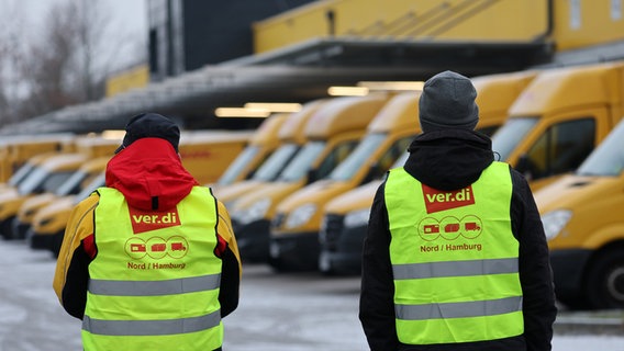 An einem Zustellstützpunkt der Deutschen Post DHL haben sich die Mitarbeitenden zum Warnstreik eingefunden, im Hintergrund stehen die Zustellfahrzeuge. © Bernd Wüstneck/dpa Foto: Bernd Wüstneck
