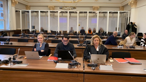 Ein Angeklagter sitzt im Landgericht Hamburg mit seiner Verteidigerin. Im Hintergrund sind Besucherinnen und Besucher des Prozesses. © NDR/Elke Spanner Foto: Elke Spanner