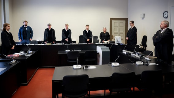 Mehrere Personen stehen in einem Gerichtssaal am Landgericht Hamburg. © dpa Foto: Christian Charisius