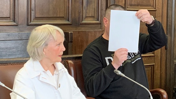 Ein Angeklagter verdeckt im Hamburger Landgericht sein Gesicht mit einem Blatt Papier. Er soll seine Frau zu Tode misshandelt haben. © NDR Foto: Elke Spanner
