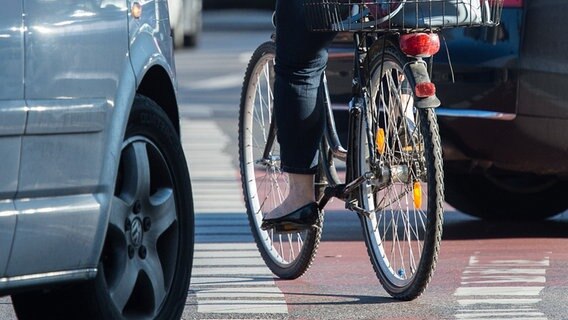 Eine Fahrradfahrerin radelt auf einem Radweg, während Autos rechts abbiegen. © picture alliance/dpa Foto: Silas Stein