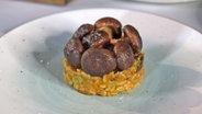 Veganes Risotto mit Shiitake-Pilzen garniert serviert. © NDR Foto: Dave Hensel