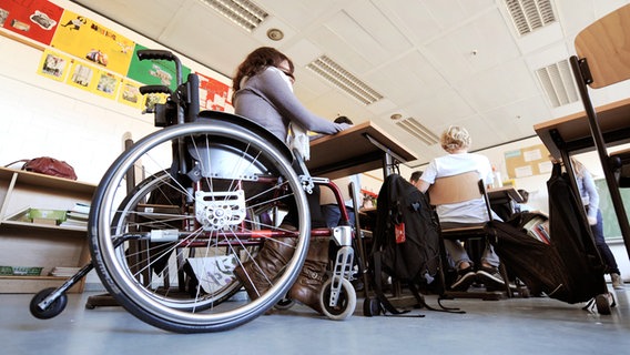 Eine behinderte Schülerin sitzt in ihrem Rollstuhl im Klassenraum einer Schule. Eine behinderte Schülerin sitzt in ihrem Rollstuhl im Klassenraum einer Schule. © dpa/picture-alliance Foto: Holger Hollemann