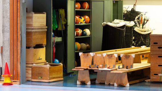 Bälle verschiedener Sportarten liegen in einem Schrank in einer Turnhalle. © picture alliance Foto: Jürgen Schwarz