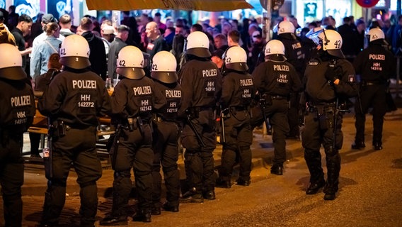 Polizisten in Schutzausrüstung sind an der Reeperbahn im Einsatz um zu verhindern, dass Fan-Gruppen der beiden rivalisierenden Stadtvereine HSV und FC St. Pauli aufeinandertreffen. © dpa Foto: Jonas Walzberg