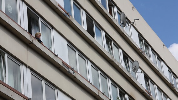 Frau schaut aus einem Fenster in einem Plattenbau-Hochhaus. © NDR Foto: Oliver Diedrich