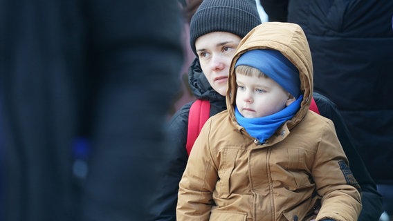 Eine Frau aus der Ukraine und ihr Sohn sitzen vor der Zentralen Ausländerbehörde an der Hammer Straße in Hamburg und warten auf Einlass. © dpa Foto: Marcus Brandt