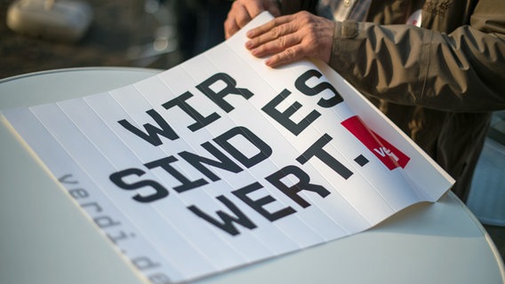 Ein Fächer mit der Aufschrift "Wir sind es wert." liegt auf einem Tisch © picture alliance / dpa Foto: Arne Immanuel Bänsch