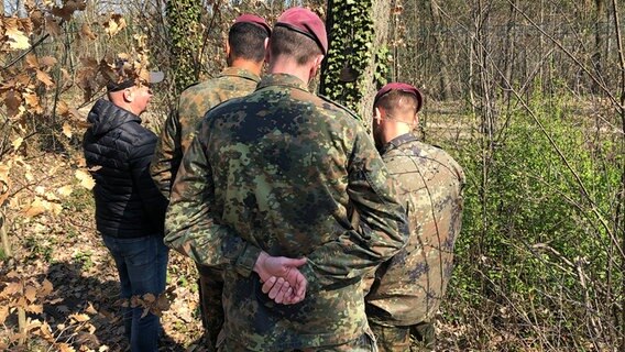 Mehrere Soldaten stehen an einer Gedenkstätte in einem "Wald der Erinnerung". © NDR 