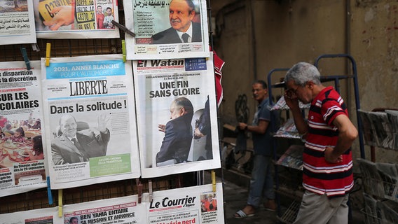 Zeitungen an einem Kiosk in Algier, daneben ein Mann. © picture alliance Foto: Billel Bensalem