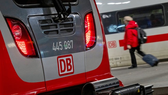 Eine Regionalbahn und ein ICE der Deutschen Bahn stehen nebeneinander in einem Bahnhof, während eine Frau mit einem Koffer vorbeiläuft. © dpa bildfunk Foto: Peter Kneffel