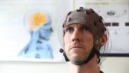 Ein Mann mit einer EEG Haube © picture alliance 