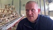 Bio-Landwirt Carsten Bauck gibt in seinem Hühnerstall ein Interview.  