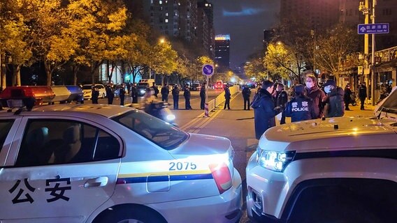 Polizieautos und Polizisten stehen auf einer Straße in Peking. © dpa bildfunk/TASS 