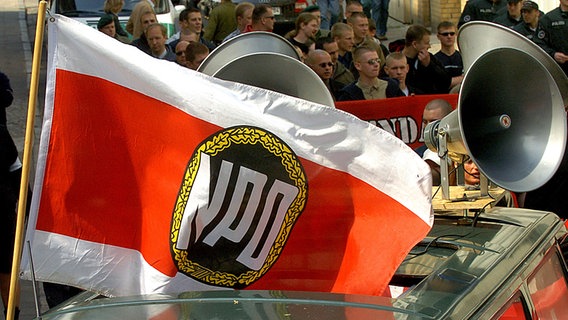 Eine Fahne mit dem Symbol der NPD und Lautsprecher, die auf ein Fahrzeug montiert sind, bei einer Demonstration © dpa-Report Foto: Jens Büttner