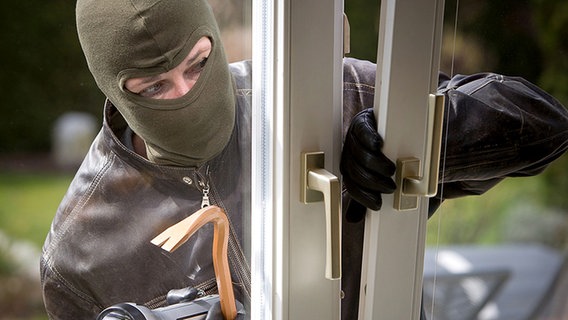 Maskierter Einbrecher bricht ein Fenster auf. © Fotolia.com Foto: bilderbox