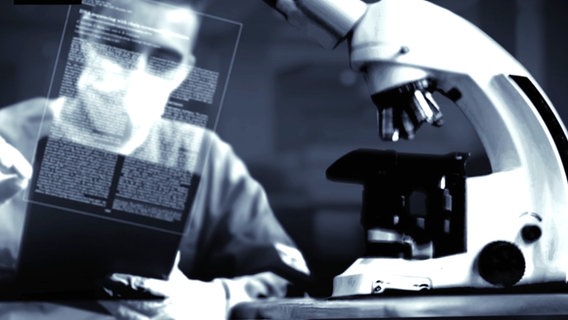 Ein Mann sitzt vor einem Mikroskop. © Screenshot 